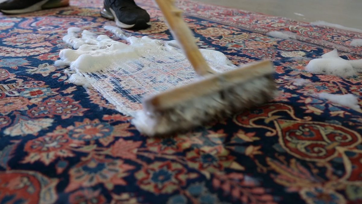 Traditional cleaning of Persian rug using brush